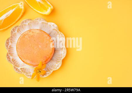 Plaque avec barre de shampooing solide, fleur et orange sur fond de couleur Banque D'Images