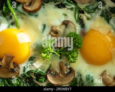 Idée pour le petit déjeuner. Deux œufs aux épinards, champignons et fromage. Plat maison sain pour un régime pauvre en glucides. Vue de dessus. Macro-alimentation Banque D'Images