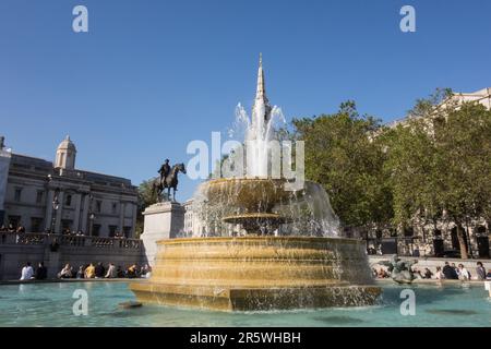 Les gens se détendent à côté d'une fontaine d'eau étincelante à Trafalgar Square, dans le West End de Londres Banque D'Images