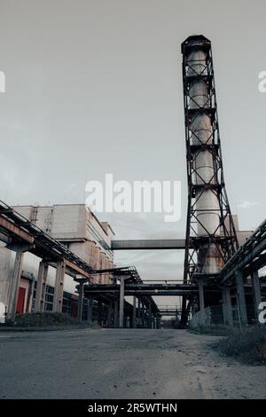 Vue panoramique d'une zone industrielle abandonnée avec une grande tour d'eau cylindrique au centre, entourée de structures en ruines et de debr Banque D'Images