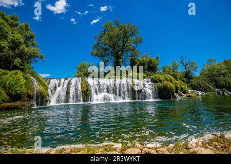 Une cascade majestueuse en cascade au milieu d'une végétation luxuriante et d'arbres, au milieu d'un magnifique ciel bleu Banque D'Images