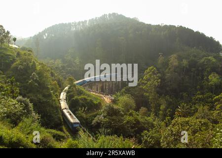 Train de passagers bleu passant par le célèbre et emblématique pont neuf Arches près d'Ella, Sri Lanka, coucher de soleil Banque D'Images
