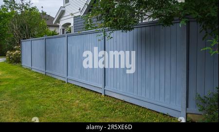 Belle clôture en bois autour de la maison. Clôture en bois avec pelouse verte. Photo de rue, personne, mise au point sélective Banque D'Images