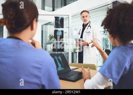 Ils se réunissent pour évaluer le problème. un médecin mature analysant les rayons x avec ses collègues lors d'une réunion à l'hôpital. Banque D'Images