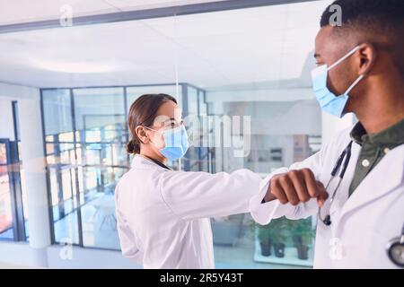 Messages d'accueil pour aplatir la courbe. deux médecins méconnaissables portant un masque et un coude qui se cognent à l'hôpital. Banque D'Images