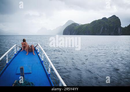 El Nido, Palawan, Philippines - 1 mars 2023 : couple assis à l'arc du bateau pour se détendre et profiter du paysage brumeux Banque D'Images