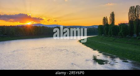 magnifique lever de soleil sur le front de mer de la rivière uzh. beau paysage urbain du centre-ville d'uzhhorod au printemps. remblai herbeux de la plus longue allée de linden dedans Banque D'Images