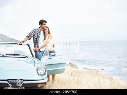 Profitez d'une vue magnifique. Un jeune couple romantique debout à côté de leur cabriolet pendant un voyage. Banque D'Images