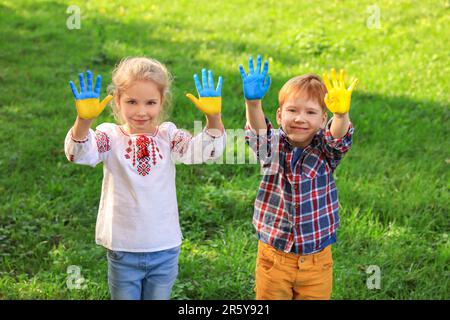 Petite fille et garçon avec les mains peintes dans les couleurs de drapeau ukrainien dehors. Love Ukraine concept Banque D'Images