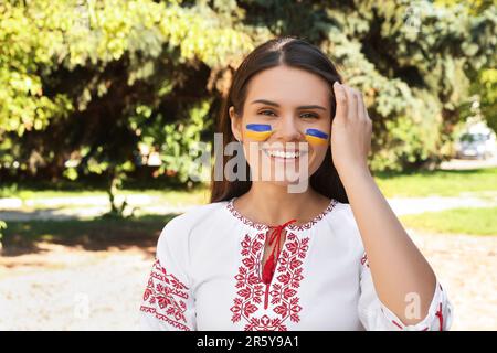 Jeune femme avec des dessins de drapeau ukrainien sur le visage dans le parc Banque D'Images