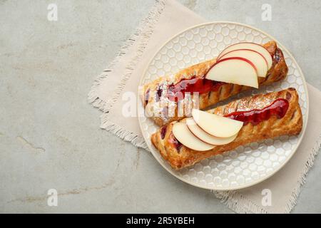 Pâte fraîche savoureuse avec confiture et pommes sur table texturée blanche, vue du dessus. Espace pour le texte Banque D'Images