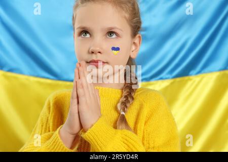 Petite fille avec des mains peintes en claqué près du drapeau ukrainien Banque D'Images