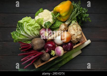 Caisse pleine de différents légumes sur une table en bois noir, vue du dessus. Récolte agricole Banque D'Images