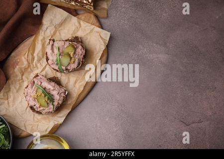 Délicieux sandwiches de livrewurst avec concombre mariné et moutarde sur table grise, vue de dessus. Espace pour le texte Banque D'Images