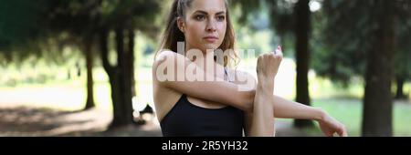 Belle femme étire les bras avant de s'entraîner dans le parc Banque D'Images