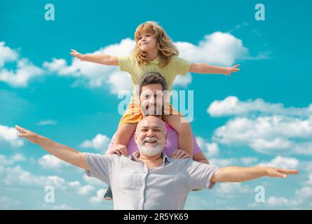 Famille générationnelle.Père, fils et grand-père famille heureuse de plusieurs genration avec les mains levées ou les bras ouverts volant sur le ciel. Banque D'Images