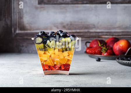 salade de fruits dans un verre. salade avec un verre coupé de fraises, bleuets, kiwi, orange et pêche, photo créative à l'ancienne Banque D'Images