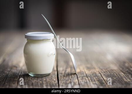 Yaourt blanc en pot sur la table en bois. Banque D'Images