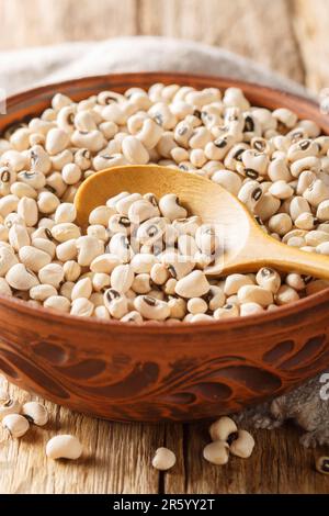Gros plan de pois noirs biologiques crus dans un bol sur une table en bois. Verticale Banque D'Images