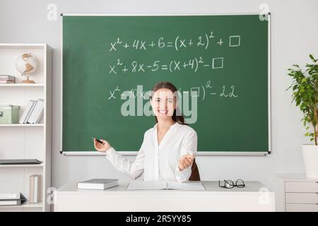 Un jeune professeur de mathématiques donne une leçon à table en classe Banque D'Images