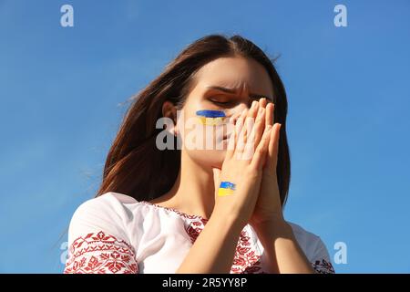 Jeune femme ukrainienne aux mains clashed contre le ciel bleu Banque D'Images