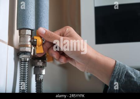 Femme qui allume la vanne de la chaudière à gaz à l'intérieur, en gros plan Banque D'Images