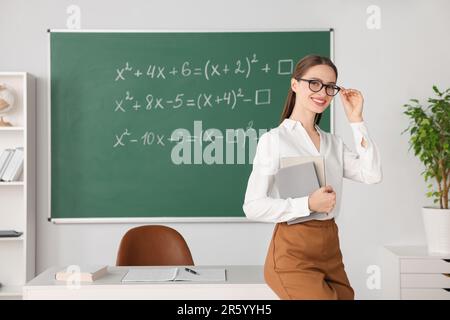 Portrait du jeune professeur de mathématiques près du tableau noir en classe Banque D'Images