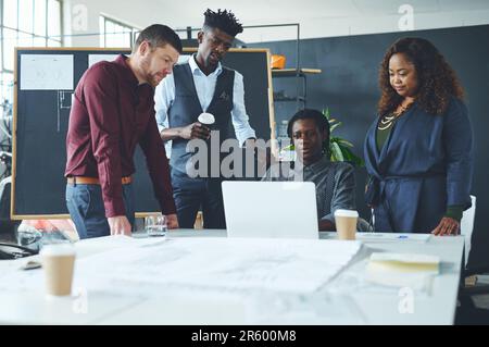 Collaborer sur un projet important. un groupe de collègues discutant de quelque chose sur un ordinateur portable pendant une réunion. Banque D'Images