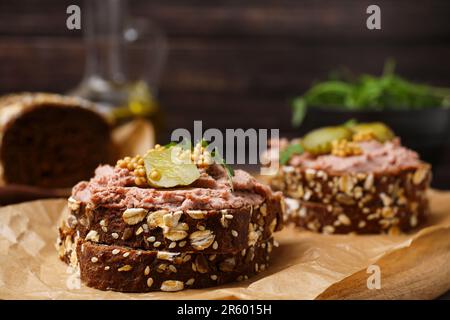 Délicieux sandwichs de livrewurst avec concombre mariné et moutarde sur panneau de bois, en gros plan Banque D'Images