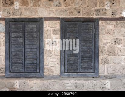 Ancienne muraille d'époque de calcaire de sable ancien et deux fenêtres fermées avec volets en bois vue de face rapprochée Banque D'Images