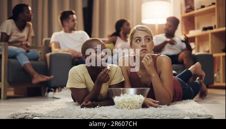 Amis, pop-corn et film à la maison le soir pour se divertir et se détendre pour le plaisir. Ami, ensemble et regarder la télévision dans le salon avec un en-cas Banque D'Images