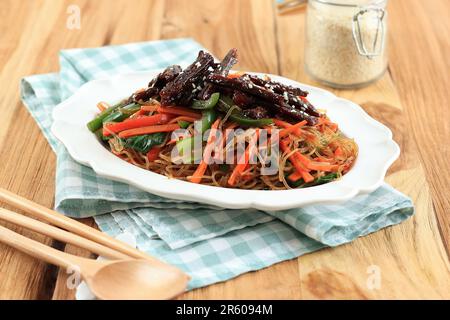 Nourriture coréenne, bœuf sauté et nouilles en verre avec Japchae végétal. Surmontée de graines de sésame Banque D'Images