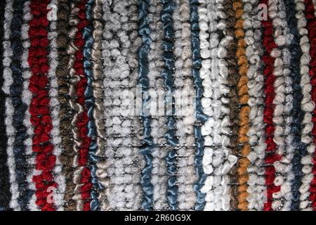 Gros plan d'un tapis rayé multicolore avec des boucles tissées épaisses. Offre un mélange vibrant de tons rouge, bleu, gris, marron et blanc. Parfait pour desi Banque D'Images