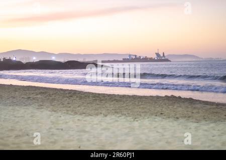 Plage de Cabeçudas dans itajai-sc brésil, en fin d'après-midi et les gens sur leur dos appréciant la plage, cargo arrivant dans la ville en arrière-plan, s Banque D'Images