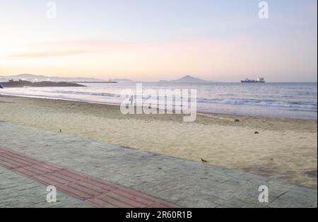 Plage de Cabeçudas dans itajai-sc brésil, en fin d'après-midi et les gens sur leur dos appréciant la plage, cargo arrivant dans la ville en arrière-plan, s Banque D'Images
