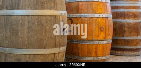 Une image en gros plan de plusieurs fûts de vin en bois avec des anneaux et des sangles en métal reposant sur un sol en ciment Banque D'Images