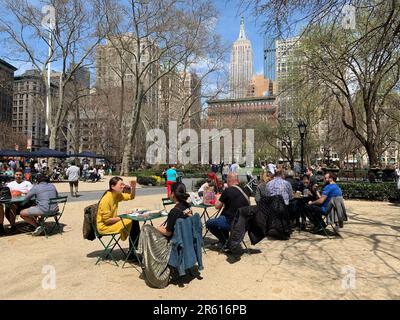 Les gens apprécient une chaude et ensoleillée journée de printemps dans un café en plein air à New York Banque D'Images