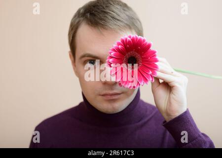 Jeune homme tenir gerbera flower dans la main. Banque D'Images