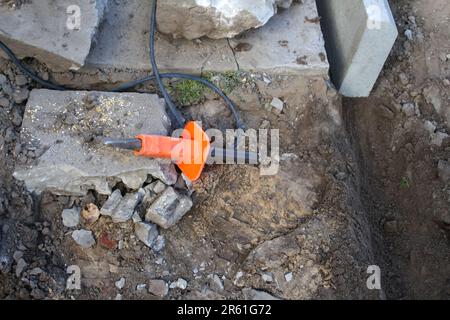 Le burin de défocalisation et la baïonnette de la pelle reposent sur le sol. Jeu d'outils pour la pose de pavés. Outils de base pour démolir et réparer. Flou Banque D'Images