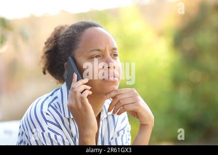 Femme noire suspecte appelant au téléphone dans un parc Banque D'Images