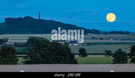 Supermoon pleine lune se levant à côté de Byres Hill au crépuscule ou au crépuscule, East Lothian, Écosse, Royaume-Uni Banque D'Images