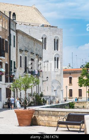 Touristes marchant sur les murs anciens avec la basilique pontificale ou l'église Saint-Nicolas et l'olivier dans un vase dans la vieille ville de Bari, Puglia ou Apulia Banque D'Images