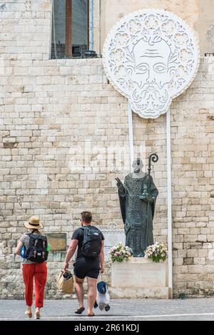 Statue en bronze de Saint Nicolas à côté de la basilique pontificale ou de l'église Saint Nicolas dans la vieille ville de Bari, Puglia, Italie avec quelques touristes à pied Banque D'Images