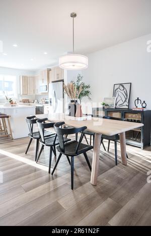 Une table à manger contemporaine en bois dans une spacieuse pièce blanche, avec quatre chaises assorties Banque D'Images