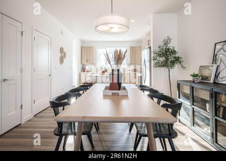 Une table à manger contemporaine en bois dans une spacieuse pièce blanche, avec quatre chaises assorties Banque D'Images