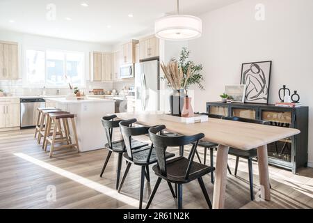 Une table à manger contemporaine en bois dans une spacieuse pièce blanche, avec quatre chaises assorties Banque D'Images