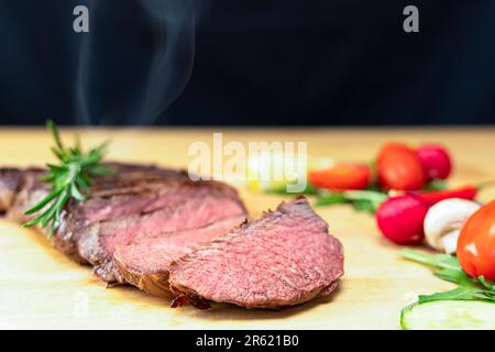 Un steak fraîchement cuit avec un côté de légumes sur une table en bois Banque D'Images