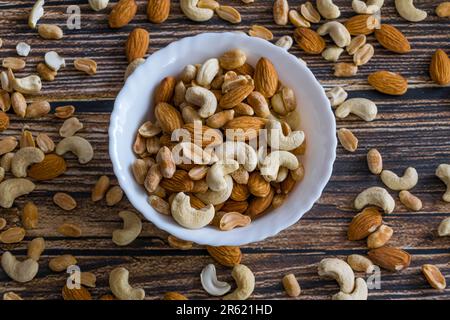 Un bol en céramique blanc isolé rempli d'une variété de noix mélangées Banque D'Images