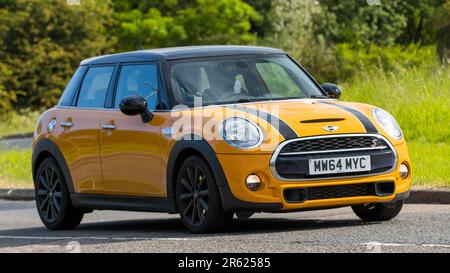 Stony Stratford, Royaume-Uni - 4 juin 2023 : 2014 mini Cooper S classique voiture de couleur orange voyageant sur une route de campagne anglaise. Banque D'Images