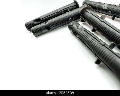 Une image rapprochée de quatre carabines noires avec des poignées en caoutchouc et des lames noires placées sur une surface blanche Banque D'Images